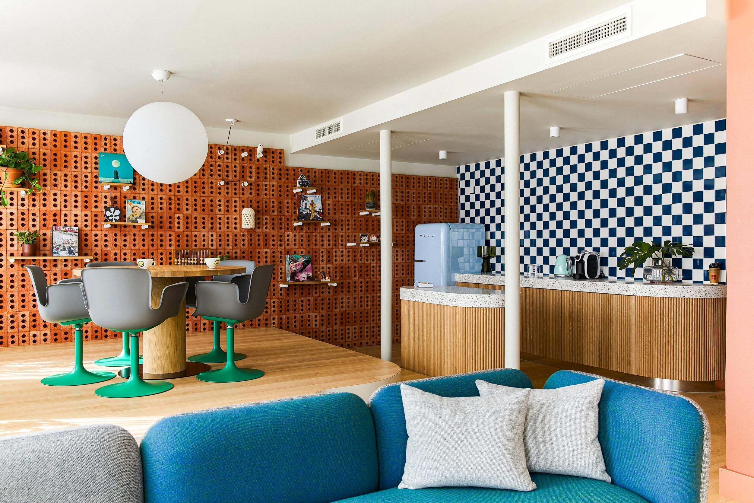A modern interior with a checkered wall, a wooden reception desk, and a blue sofa.