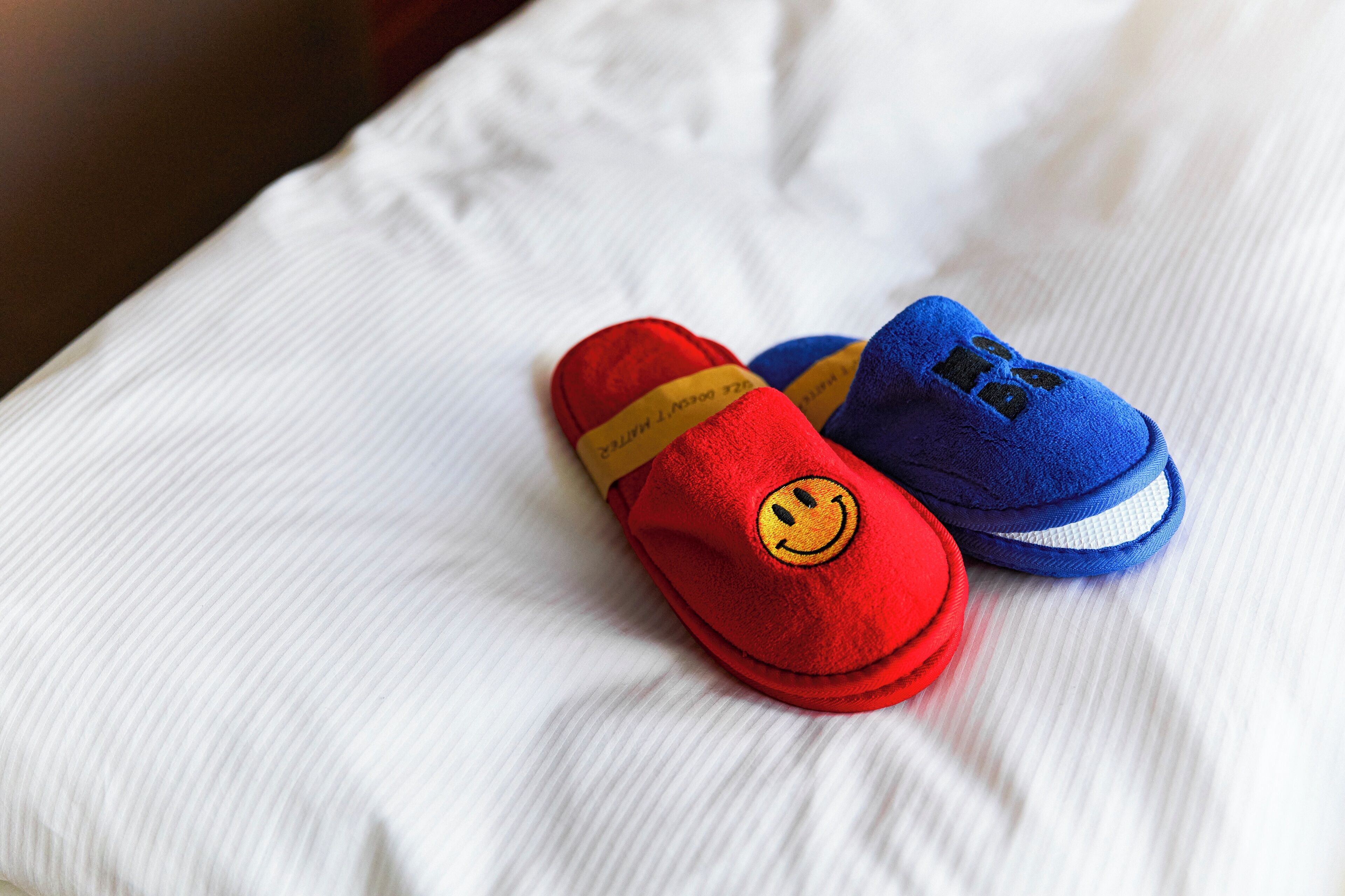 Um par de sapatos de bebê com carinhas sorridentes sobre uma superfície de tecido branco.