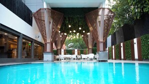 A swimming pool with a modern design, surrounded by white lounge chairs and a wooden structure with hanging lights. - Park Inn by Radisson New Delhi Lajpat Nagar (New Delhi)