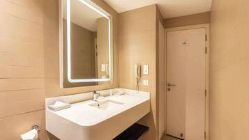 A modern bathroom with a large mirror, white sink, and a door.