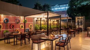 Enjoy casual dining in a welcoming outdoor space with tables set amidst a unique brick backdrop.