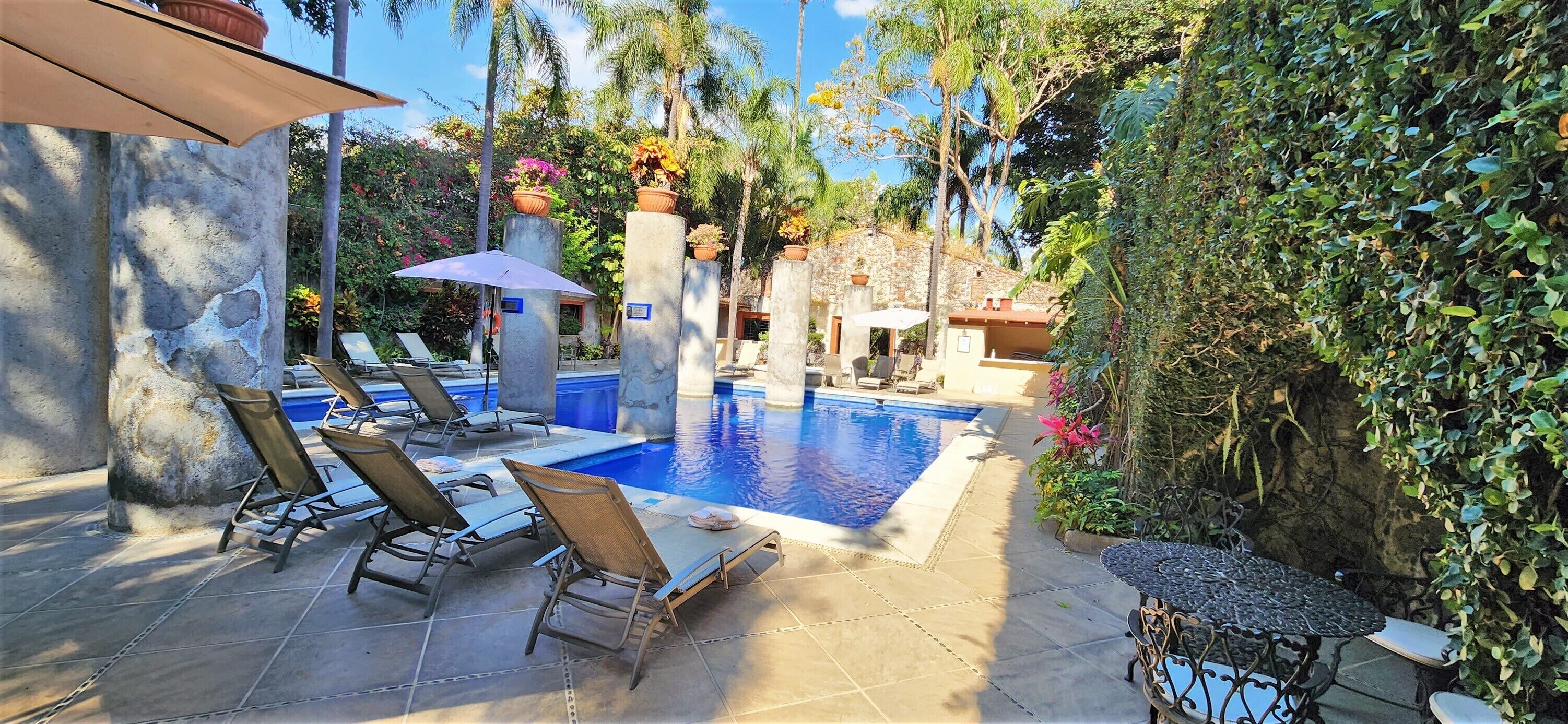 Una piscina al aire libre, sombrillas, tumbonas