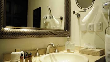 A hotel bathroom with a sink, mirror, towel, and toiletries.
