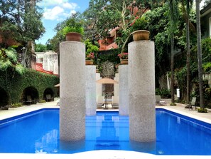 Una piscina al aire libre, sombrillas, sillones reclinables de piscina