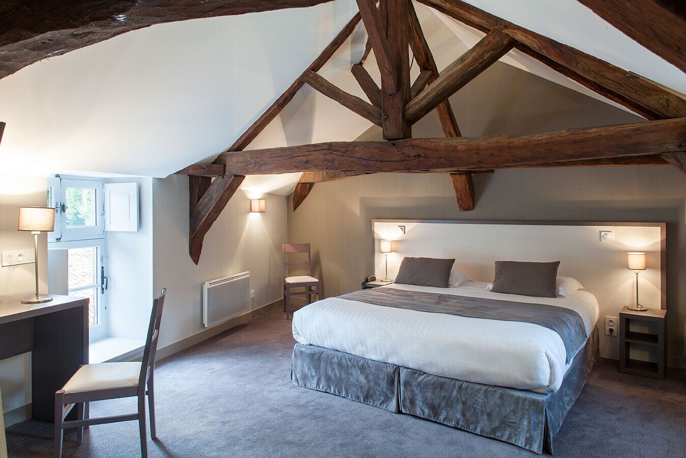 A bedroom with a large bed, a desk, and a chair.