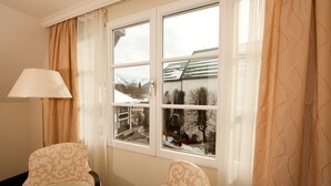 Una habitación con dos sillas, una mesa con fruta y una ventana con cortinas.