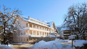 Un hotel con fachada nevada y montañas al fondo.