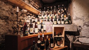 Una bodega con estantes de madera y paredes de piedra, que alberga numerosas botellas de vino.
