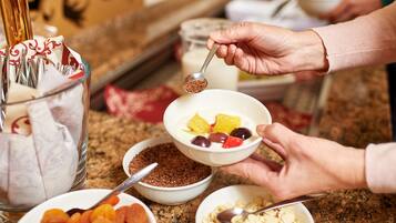 A person preparing a bowl of cereal with various toppings.