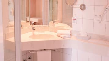 A bathroom with a sink, mirror, towel rack, and a hairdryer on the wall.