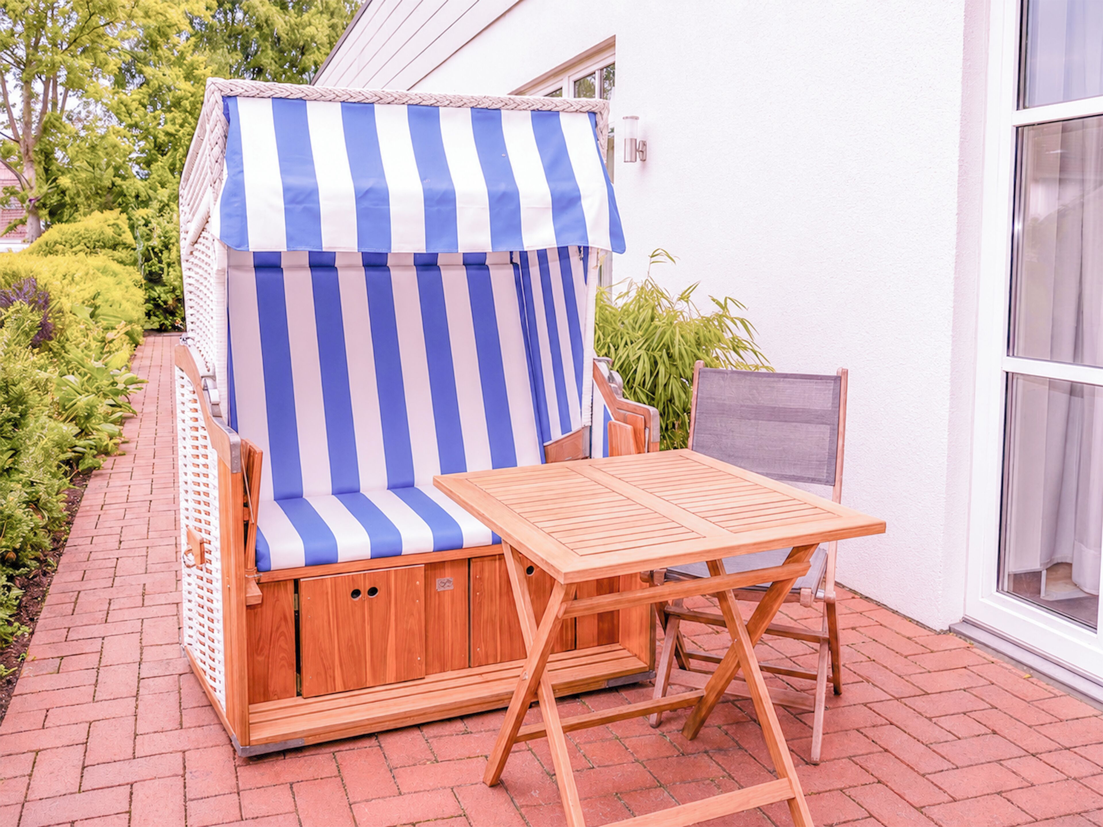 Un área de estar exterior con madera, una toldo a rayas, una mesa y una silla.
