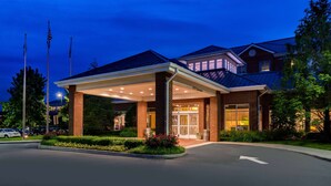 A hotel with a covered entrance, brick facade, and a well-lit driveway. - Hilton Garden Inn Charlottesville (Charlottesville)