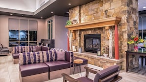 Una sala de estar moderna con chimenea de piedra, asientos cómodos y vistas al exterior.