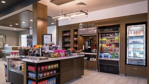 Una estación de autoservicio con bebidas y aperitivos, un refrigerador y una máquina de café.