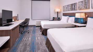 A hotel room with a desk, two beds, a TV, and artwork on the wall.