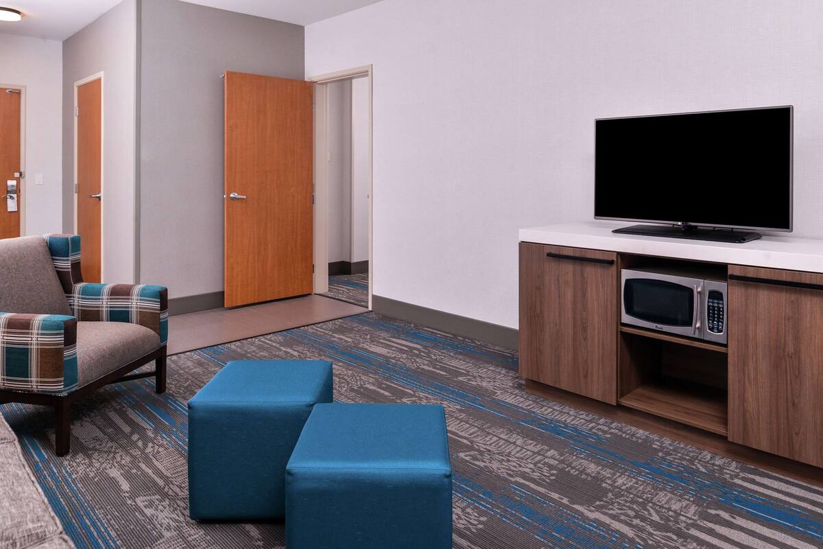 Ein Hotelzimmer mit Fernseher, Mikrowelle und Sitzgelegenheit.