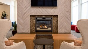 A modern living room with a fireplace, a flat-screen TV mounted on the wall, and comfortable seating.