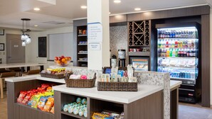A hotel lobby with a self-service beverage station, snack dispensers, and a coffee machine.