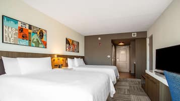 A hotel room with two beds, a TV, a painting on the wall, and a carpeted floor.