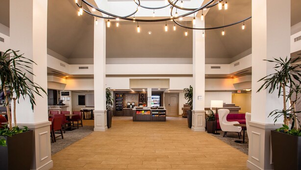 A spacious lobby with a central bar area, high ceilings, and modern lighting fixtures.