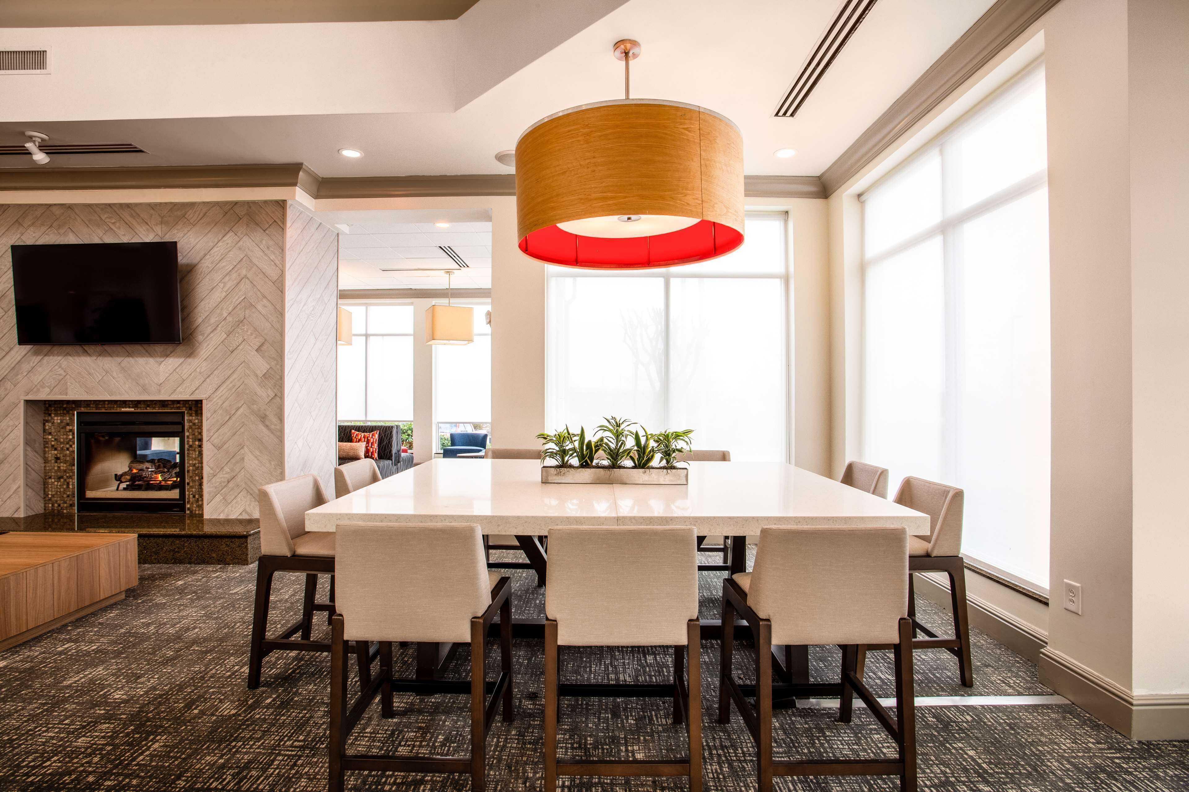 A spacious conference room with a large table, comfortable chairs, a modern pendant light, and a fireplace.