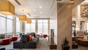A modern lobby with a sofa, red ottomans, and a fireplace.