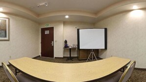 Une salle de conférence équipée d’une grande table, d’un tableau blanc et d’une porte de sortie.