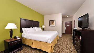 A hotel room with a bed, bedside lamps, a TV, a dresser, and a door leading to another room.