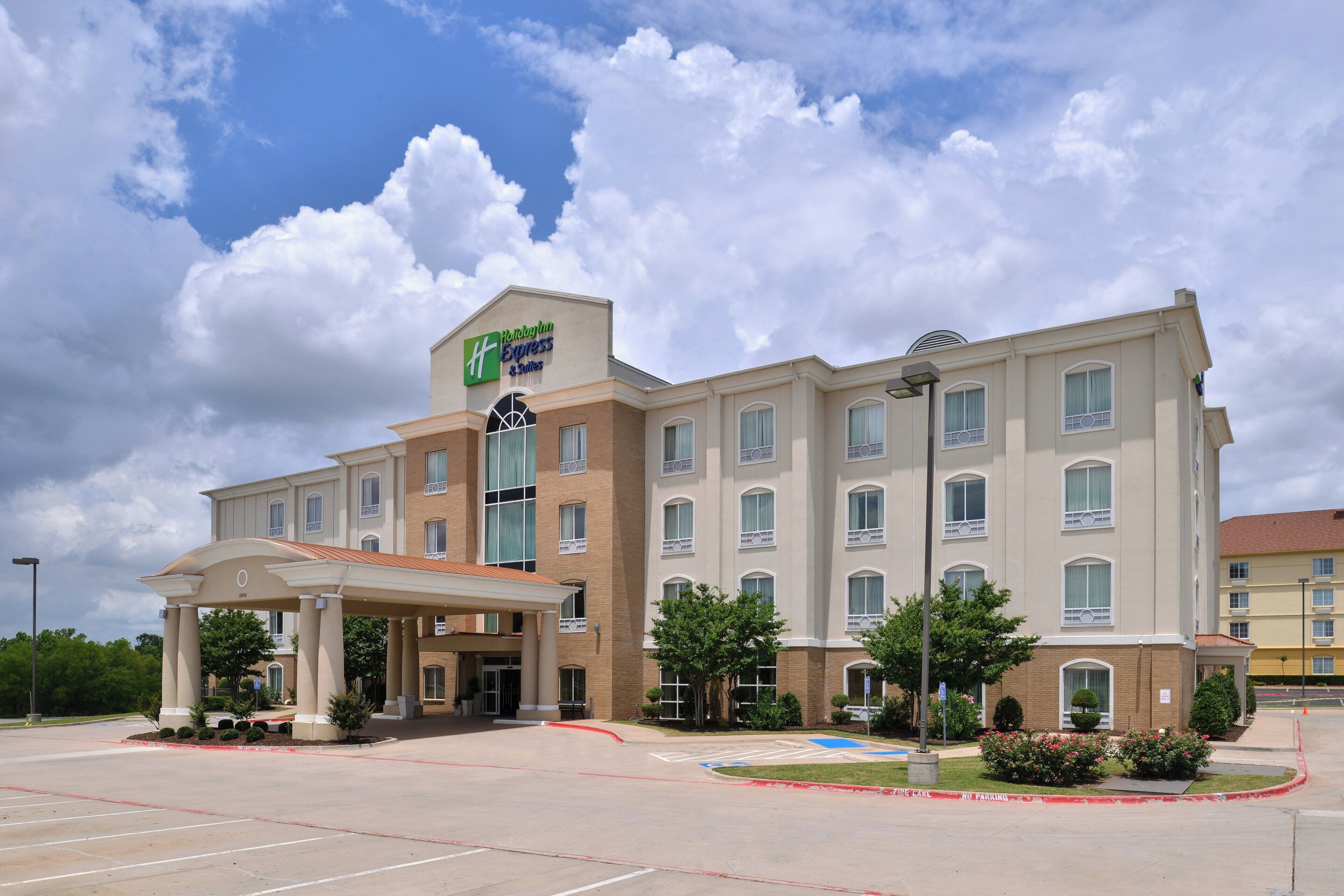 A Holiday Inn Express & Suites hotel with a covered entrance and a parking lot.