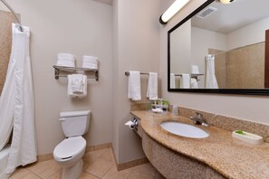 A bathroom with a toilet, sink, and mirror. There are towels on a shelf and a shower curtain. - Holiday Inn Express Hotel & Suites Sherman Highway 75 by IHG (Sherman)