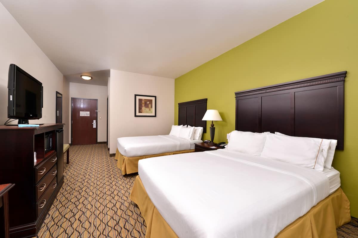 A hotel room with two beds, a TV, a desk, and a lamp.
