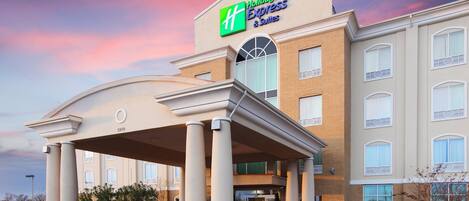 Un hotel Holiday Inn Express & Suites con entrada cubierta, columnas y fachada de ladrillo.