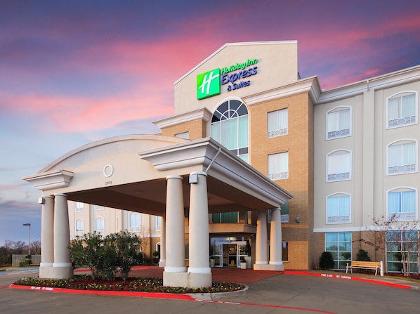 Un hotel Holiday Inn Express & Suites con entrada cubierta, columnas y fachada de ladrillo.
