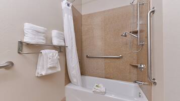 Un espace douche équipé d’une barre d’appui, d’un porte-serviettes avec des serviettes et d’un rideau de douche.