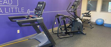 Ein Fitnessraum mit Laufband, Crosstrainer und Ergometer, sowie einer Wand mit motivierenden Texten.