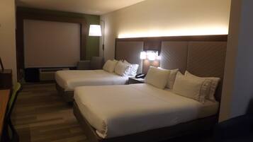 Ein Hotelzimmer mit zwei Betten, einem Schreibtisch, einem Stuhl, einer Lampe und einem Fernseher.