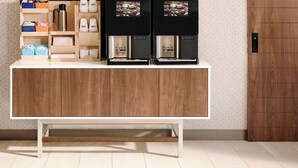 A modern kitchen with a wooden cabinet, a coffee machine, and storage shelves. - Holiday Inn Express Hotel & Suites Dyersburg by IHG (Dyersburg)