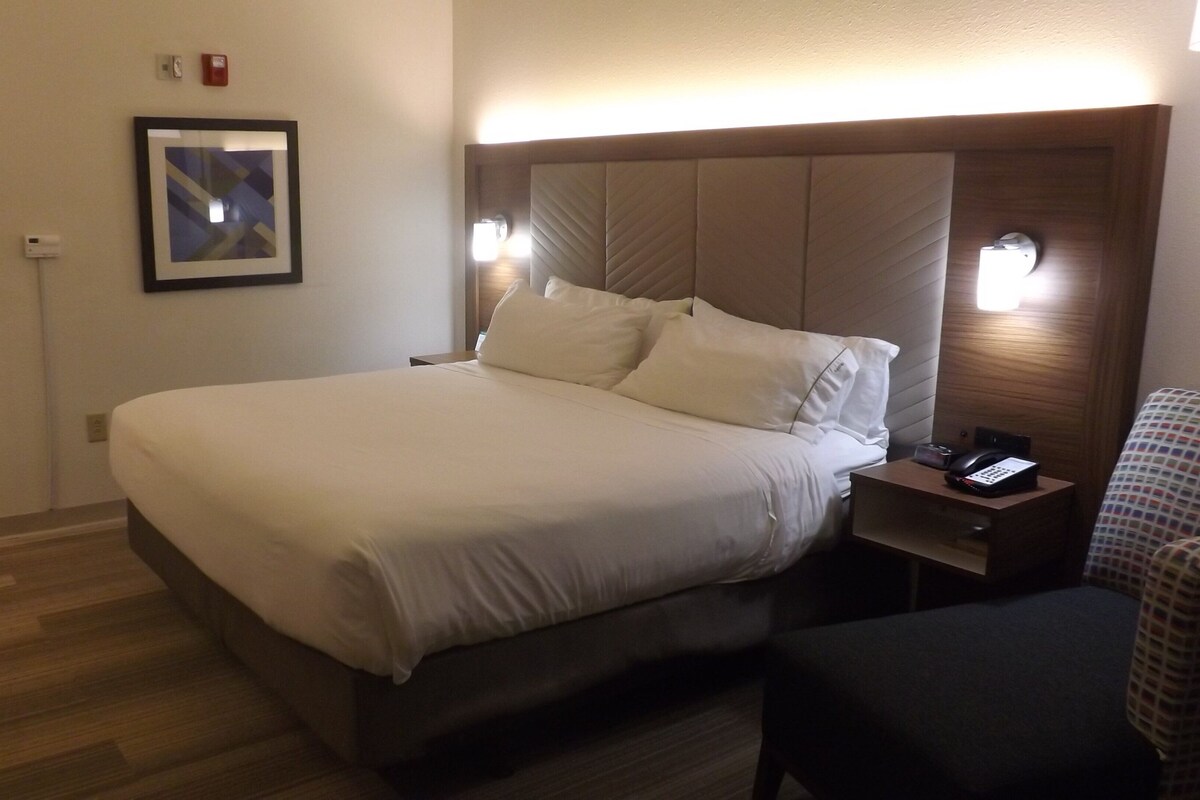 A hotel room with a large bed, bedside lamps, a telephone, and a framed picture on the wall.