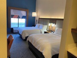 Habitación de hotel con dos camas, un escritorio y ventana con vistas.