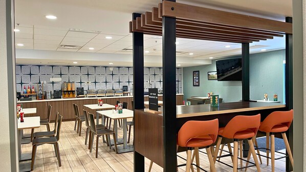 A modern breakfast area with a counter, seating, and a TV screen.