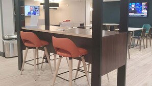 Una sala de conferencias moderna con una mesa larga, dos sillas rojas y una pantalla de televisión que muestra noticias.