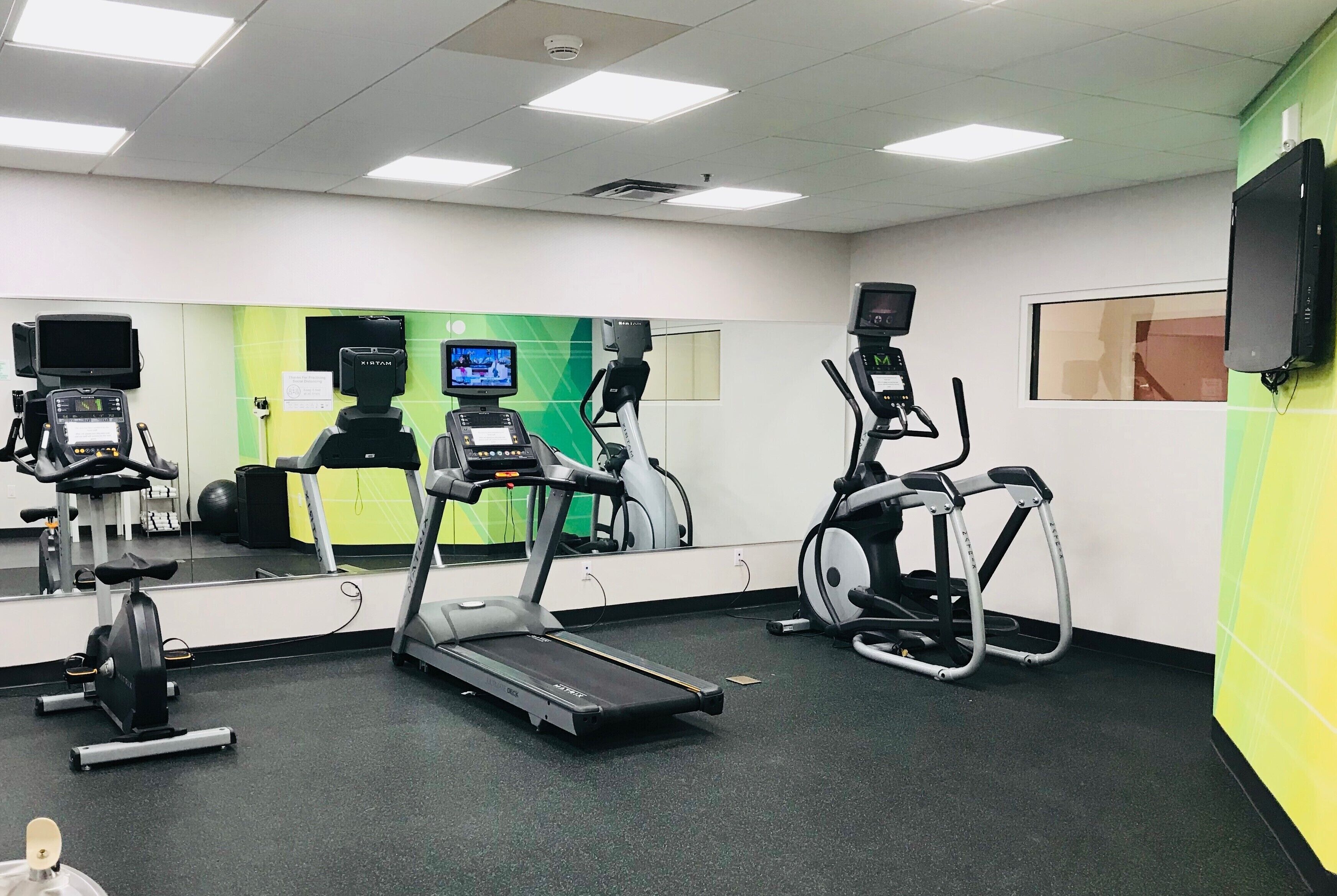 Un gimnasio con cintas de correr, elípticas y una bicicleta estática.