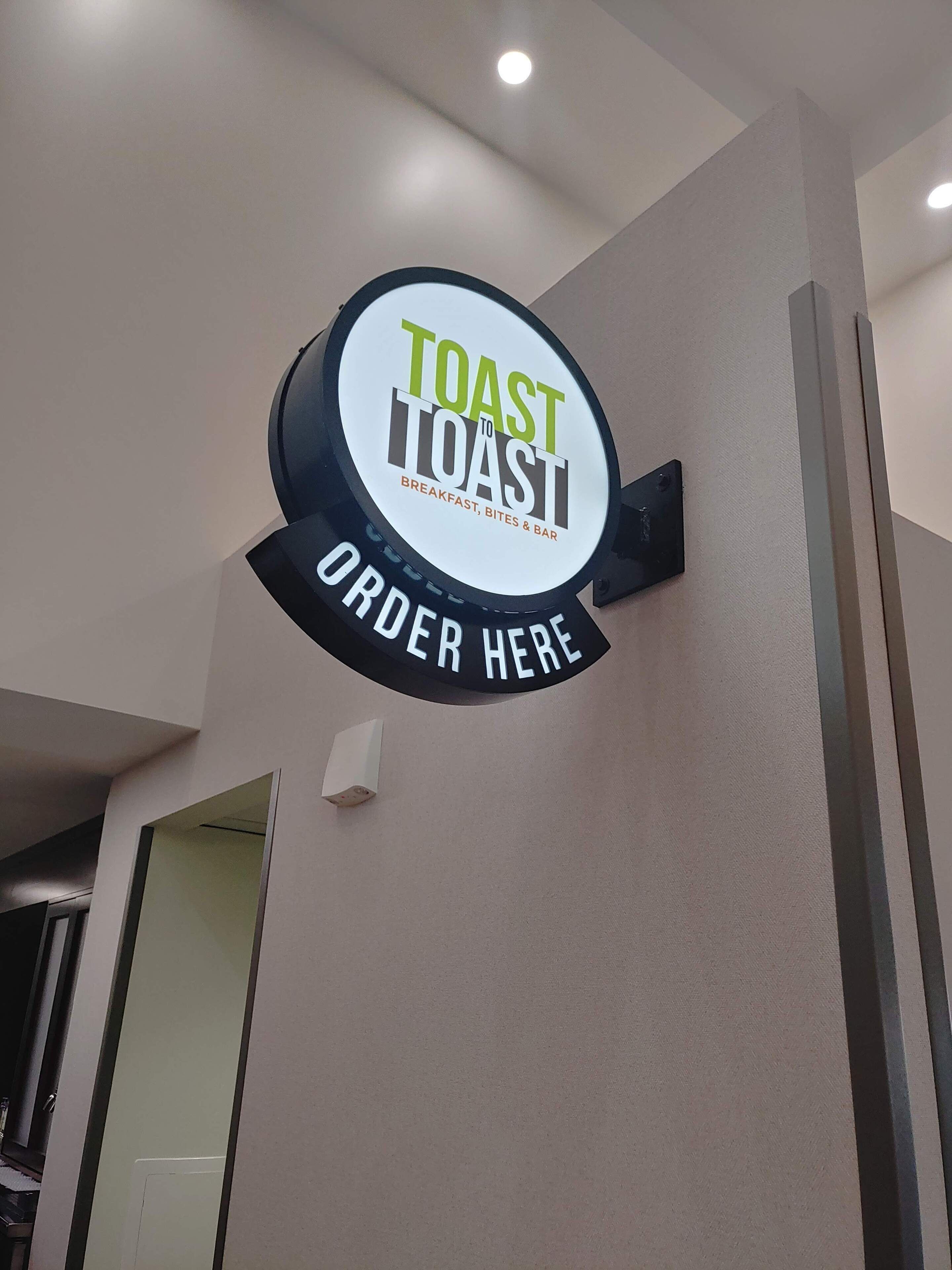 A sign for a restaurant named 'Toast to Toast' with a menu of breakfast, bites, and bar options.