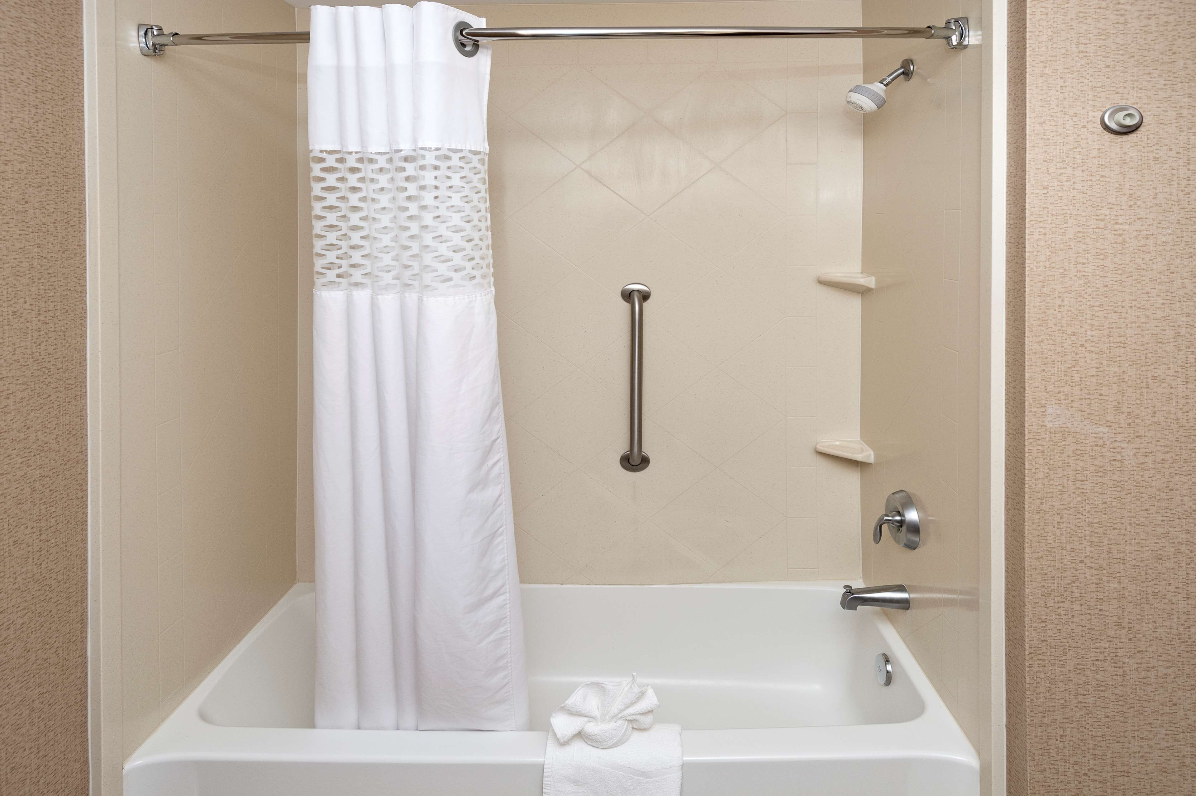 A bathroom with a bathtub, a shower with a grab bar, and a towel rack.