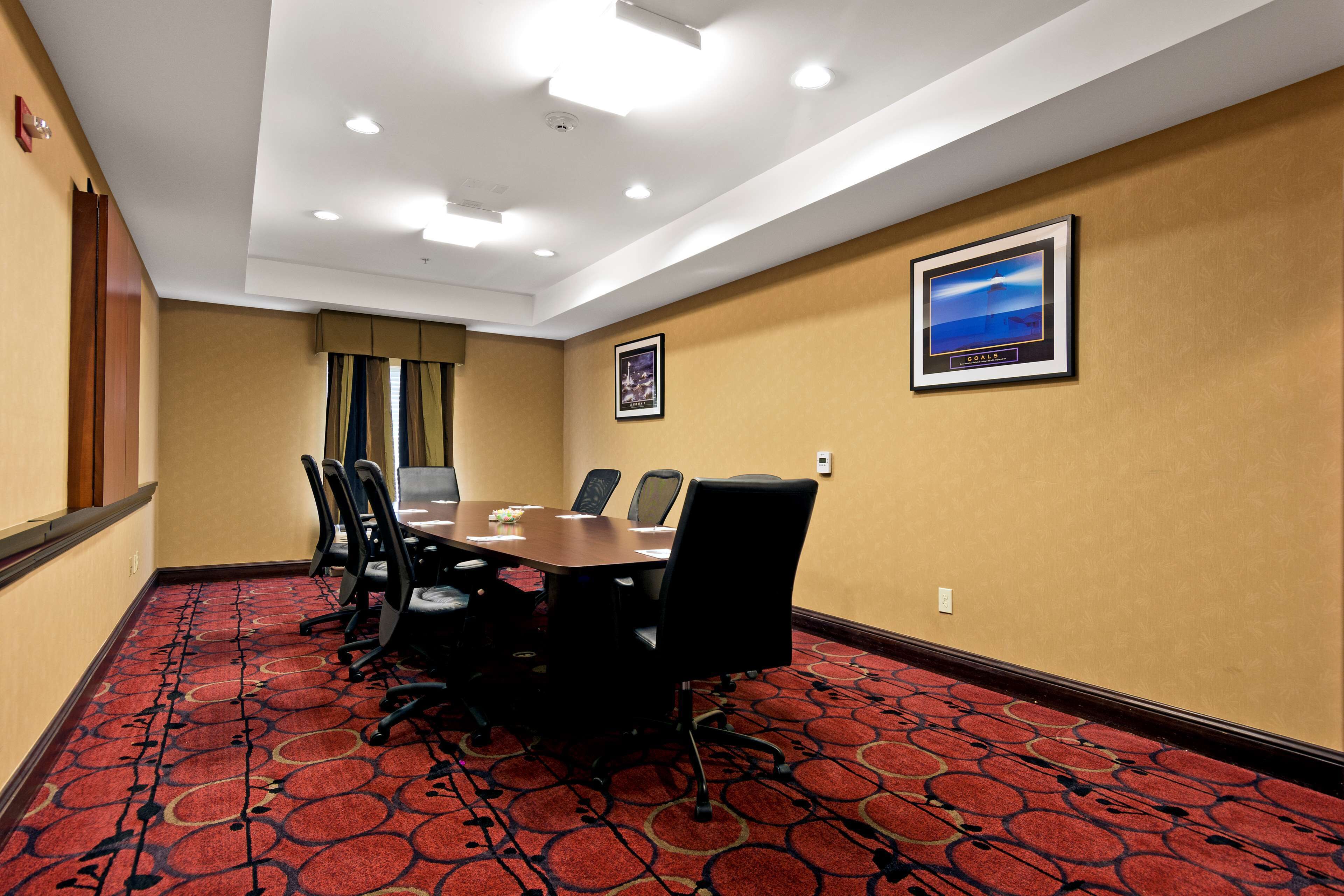A conference room with a red carpet, a white ceiling, and framed pictures on the walls.