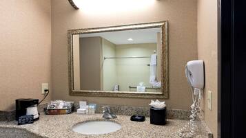 A hotel bathroom with a sink, mirror, towel rack, and a hairdryer.