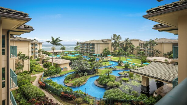 Un resort con piscina, palmeras y vista al océano.