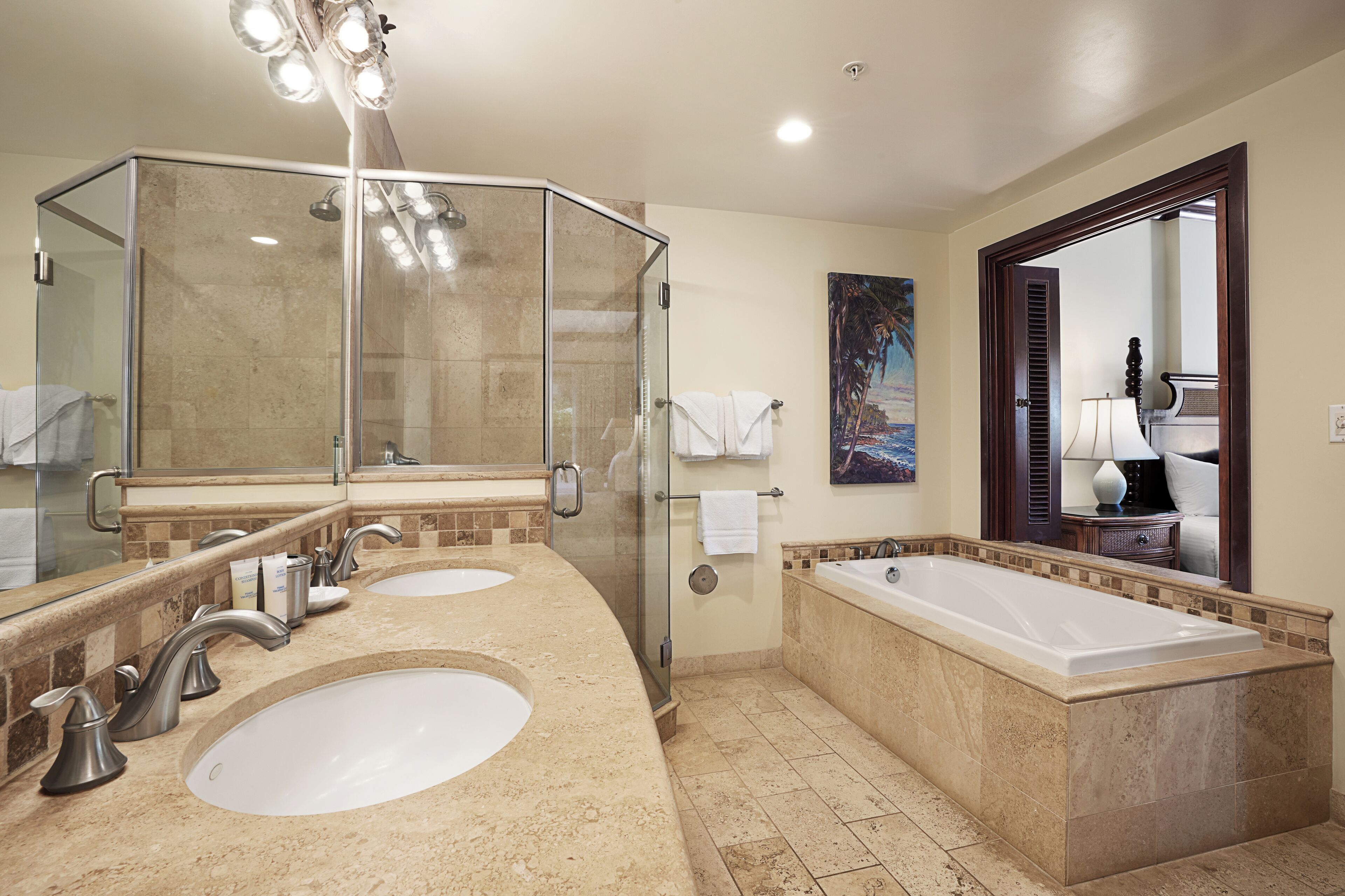 A modern bathroom with two sinks, a glass-enclosed shower, and a large bathtub.