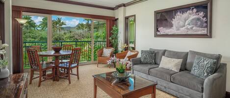 A spacious living room with a gray sofa, wooden coffee table, and a dining area with chairs and a table.