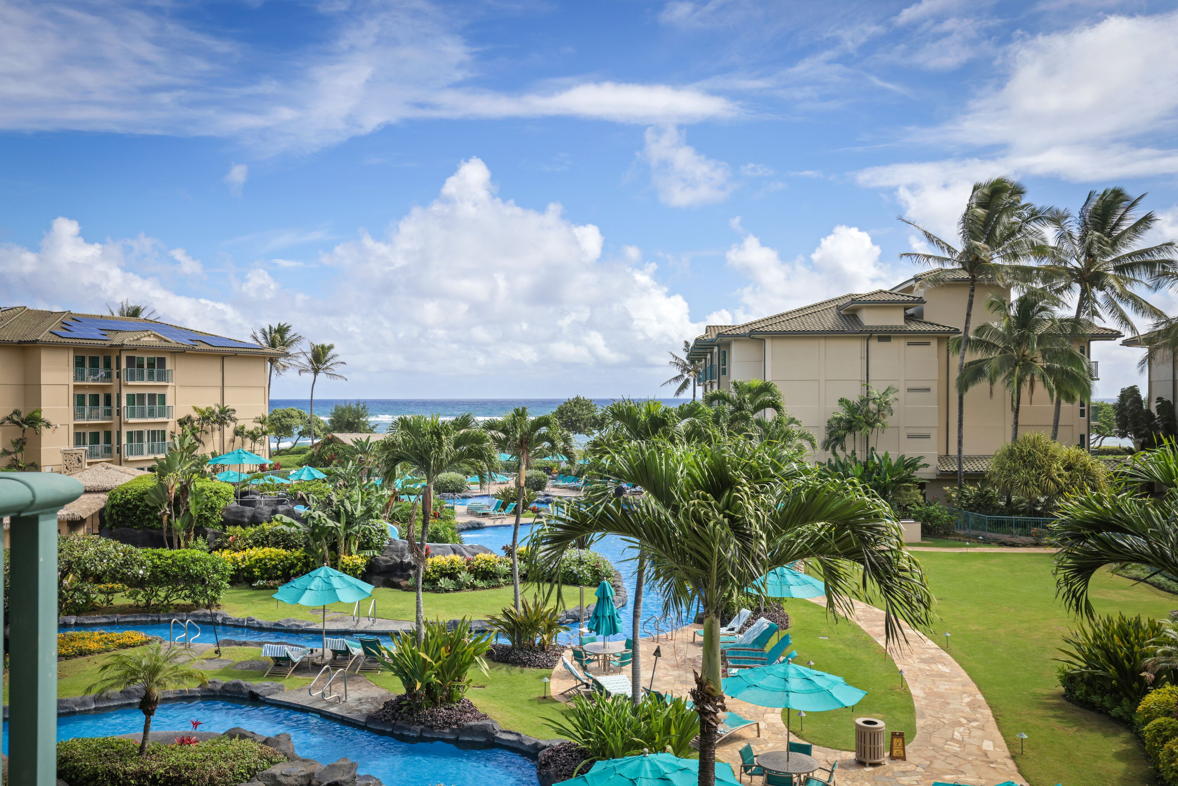 A resort with multiple swimming pools, palm trees, and a view of the ocean.